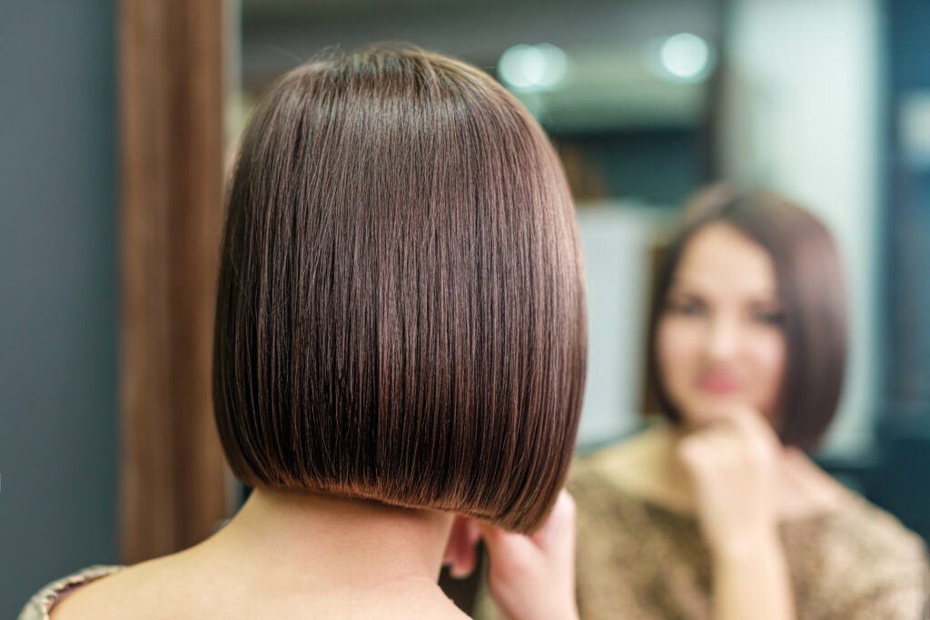 young woman is looking in the mirror with beautiful hairstyle in Lea Salon Studios
